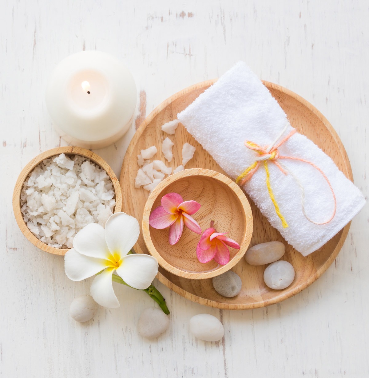 A wooden table displays various spa accessories like candles and oils